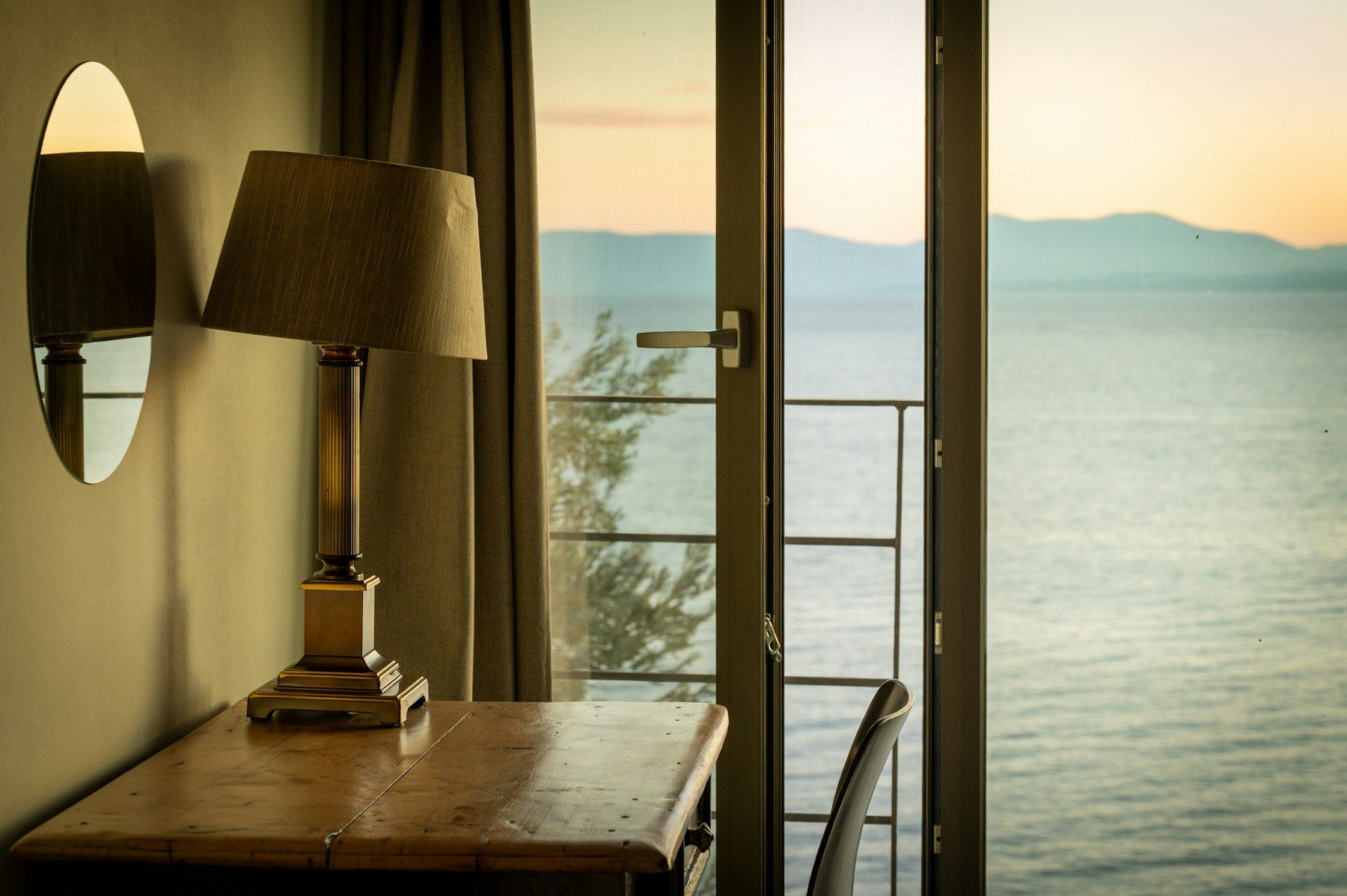 A lamp by a window with the morning sea beyond