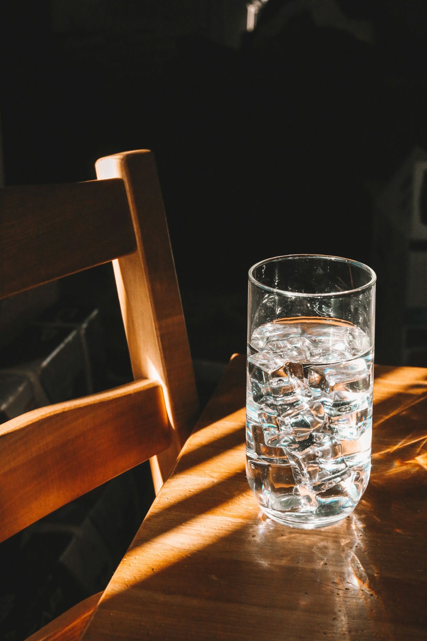 A glass of water on a wooden chair in sunlight