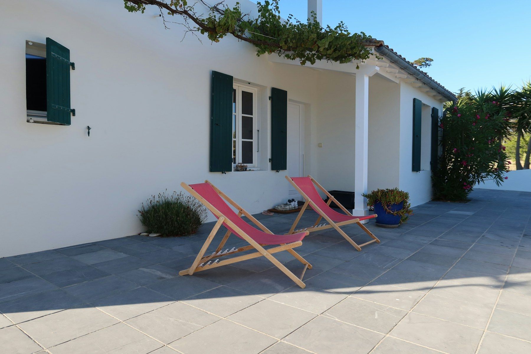 Two deck chairs on a white terrace in the sun