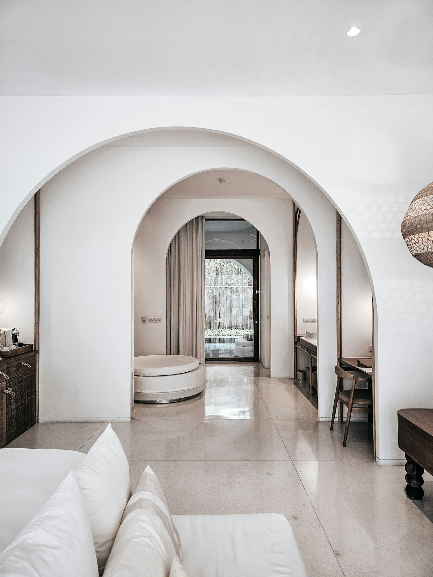 A calm white hotel suite with arched openings
