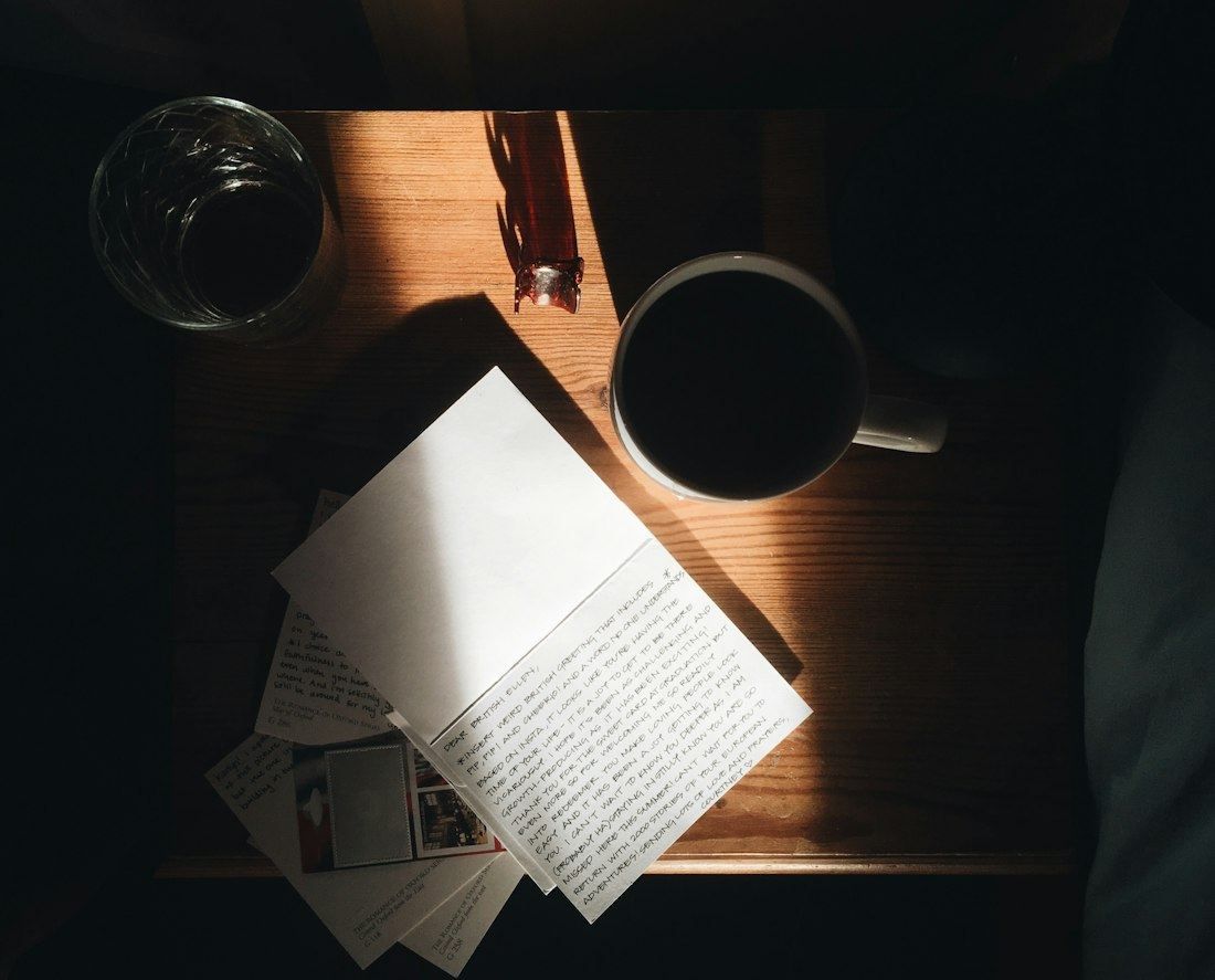 Handwritten report pages and a cup of coffee on a wooden table